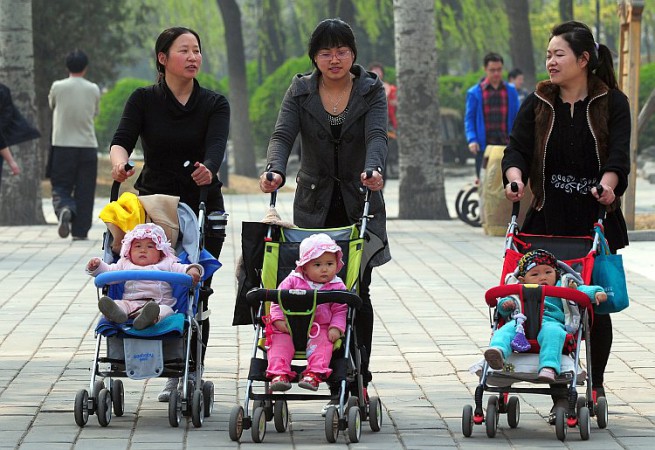 Women push babies in prams through a Bei